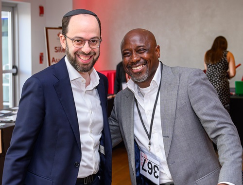 Two men standing together smiling.